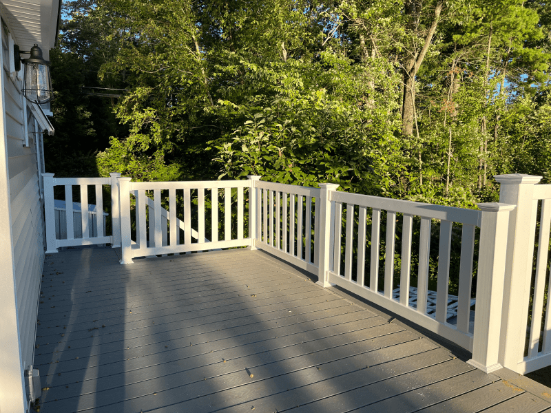 White Vinyl Picket Fence Surrounding A Wooden Deck